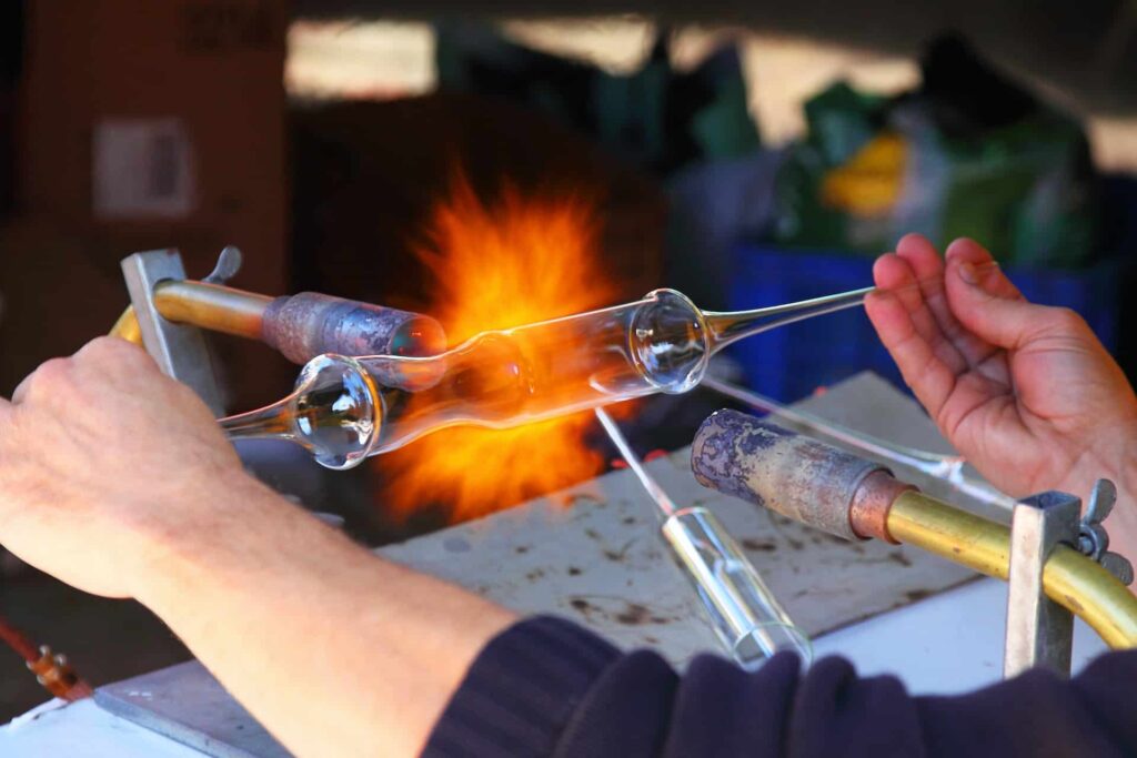 This photo shows the hands of someone with a glass tube being heated in the middle. It has already been moulded to some extend, and it's looks like they are crafting something. This depicts the way MyWebAdvantage creates unique custom design websites for businesses that are ready to stand out and grow.